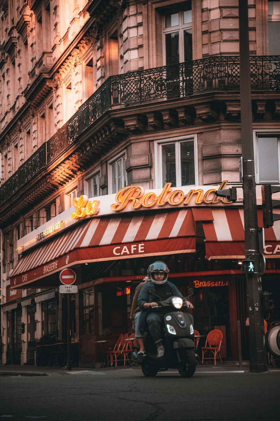 a man riding a motorcycle in front of a cafe